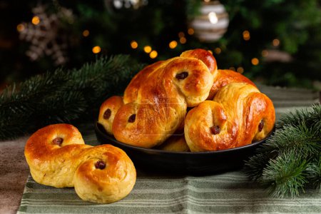 Téléchargez les photos : Petits pains au safran maison suédois Sainte-Lucie. Également appelé lussekatt ou lussebulle, le pain au thé cornique est un pain sucré épicé à la levure aromatisé au safran et contenant des raisins secs. Arbre de Noël. - en image libre de droit