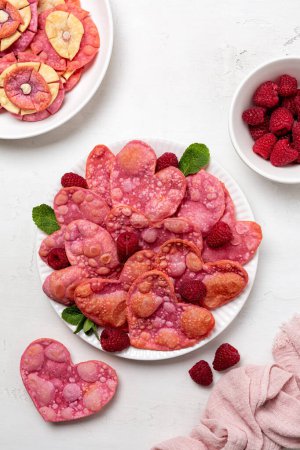 Photo for Heart shaped pink sweets, fried angel wings, coloured with beetroot. Valentine day romantic breakfast with raspberries. Vertical image. - Royalty Free Image