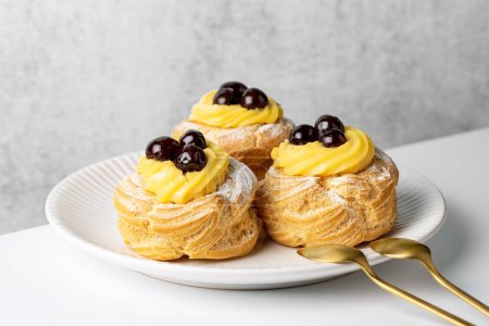 Zeppole di San Giuseppe, zeppola - baked puffs made from choux pastry, filled and decorated with custard cream and cherry.  Italian pastry traditional for Saint Joseph's Day. 