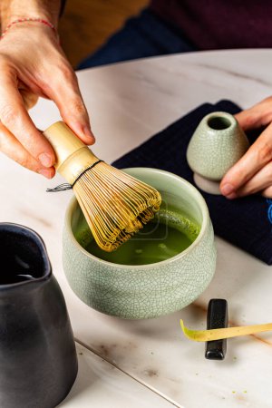 Photo for Man cooking green matcha tea  in the traditional Japanese ceremony. Bamboo whisk, spoon, or shashaku, tea into a heated tea bowl known as a chawan. Vertical image - Royalty Free Image