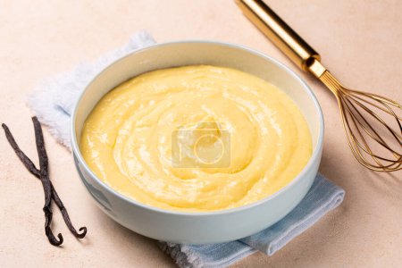Téléchargez les photos : Crème pâtissière à la vanille ou crème anglaise dans un bol bleu clair. Fabriqué avec du lait, des jaunes d'œufs et du sucre, épaissi avec de l'amidon de maïs. - en image libre de droit