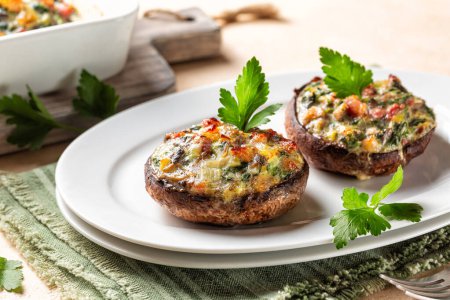 Photo for Homemade appetizer stuffed portobello mushrooms cups on a white plate,  stuffed with leek, spinach, bacon and cheese. - Royalty Free Image