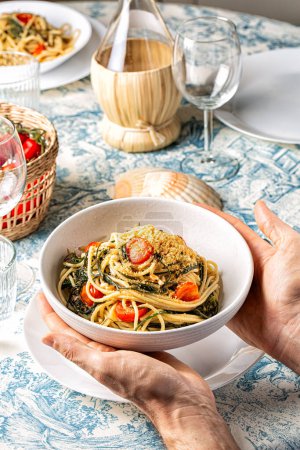 Spaghetti mit agretti oder salsola soda, Tomaten, Semmelbrösel, Pinoli-Pinienkernen und Sardellen. Italienischer Esstisch. Vertikales Bild.
