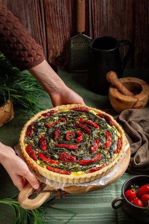 Serving italian rustic savory pie made with pie crust, salsola soda or agretti, ricotta cheese, eggs and dried tomatoes. Homemade baked food, vertical image.