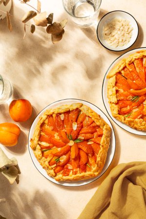 Vista superior de la galette de frutas de albaricoque con frangipane, pastel o pastel de frutas abierto con almendras y romero. Pasteles horneados caseros. Imagen vertical.