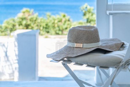 Foto de Amplio ala floja sombrero de verano en la silla con una vista increíble para el mar Egeo durante las vacaciones de verano, concepto de vacaciones de mar - Imagen libre de derechos
