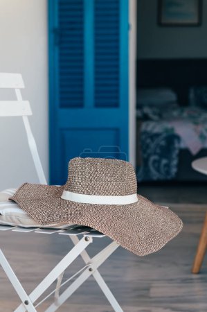 Foto de Sombrero de verano en silla con casa de campo en el fondo durante las vacaciones de verano, concepto de vacaciones de mar - Imagen libre de derechos