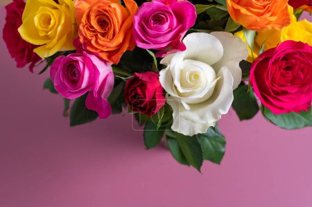 Foto de Ramo de rosas de colores. Hermoso ramo de rosas en variedad de colores sobre fondo rosa polvoriento con espacio para copiar - Imagen libre de derechos