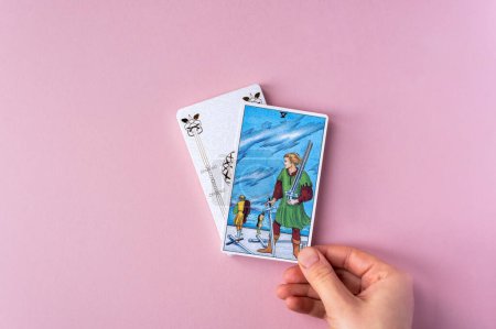 Foto de London, UK: 6 January, 2023: Minor Arcana - Five of Swords of Tarot Card of Rider Waite deck in hand on pink background - Imagen libre de derechos