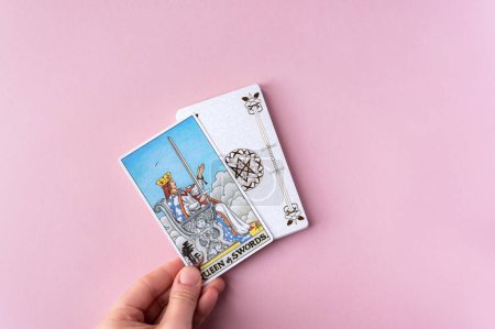 Foto de London, UK: 6 January, 2023: Minor Arcana - Queen of Swords of Tarot Card of Rider Waite deck in hand on pink background - Imagen libre de derechos