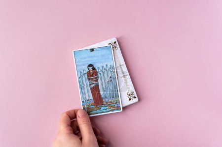 Foto de London, UK: 6 January, 2023: Minor Arcana - Eight of Swords of Tarot Card of Rider Waite deck in hand on pink background - Imagen libre de derechos