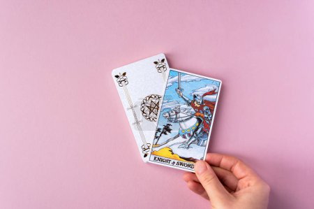 Foto de London, UK: 6 January, 2023: Minor Arcana - Knight of Swords of Tarot Card of Rider Waite deck in hand on pink background - Imagen libre de derechos