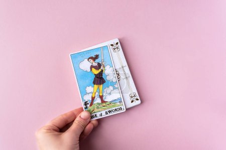 Foto de London, UK: 6 January, 2023: Minor Arcana - Page of Swords of Tarot Card of Rider Waite deck in hand on pink background - Imagen libre de derechos