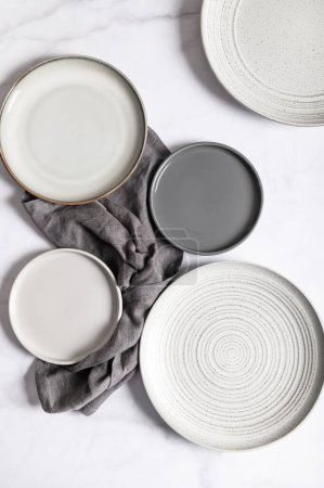 Téléchargez les photos : Assiette plate en céramique grise vide ondulée texturée avec serviette sur fond gris - en image libre de droit