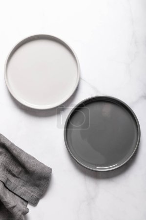 Téléchargez les photos : Assiette plate en céramique grise vide ondulée texturée avec serviette sur fond gris - en image libre de droit