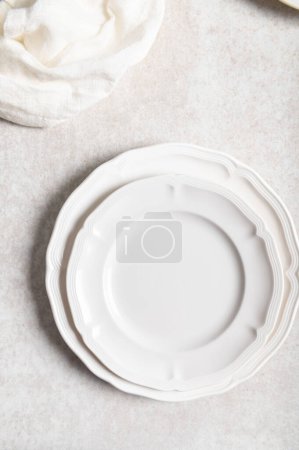 Foto de Colocación plana de placa de cerámica blanca con servilleta sobre fondo claro - Imagen libre de derechos