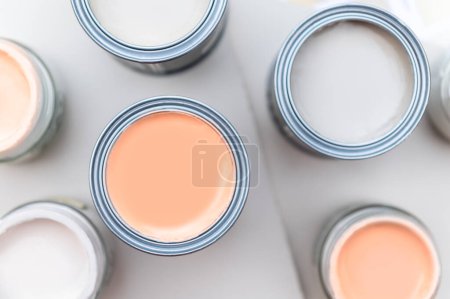 Winzige Musterfarbdosen bei der Hausrenovierung, Farbauswahlverfahren für die Wände, Peach Fuzz Farbe des Jahres 2024, Farbkarten im Hintergrund
