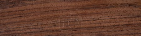 Eine Nahaufnahme, die die komplizierten Maserungen und erdigen Farbtöne der polierten Holzoberfläche aus indischem Palisander offenbart