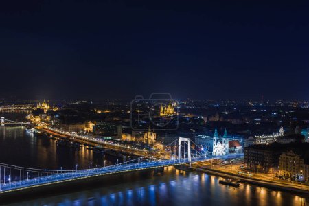 Foto de Vista nocturna de Budapest. Paisaje urbano de famoso destino turístico con Danubio y puentes. Paisaje iluminado de viaje en Hungría, Europa. - Imagen libre de derechos