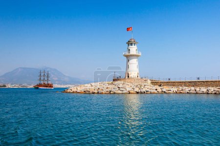 Foto de Faro en Alanya, distrito de Antalya, Turquía, Asia. Vista de la ciudad desde el barco. Destino turístico popular. Agua clara en día soleado
. - Imagen libre de derechos