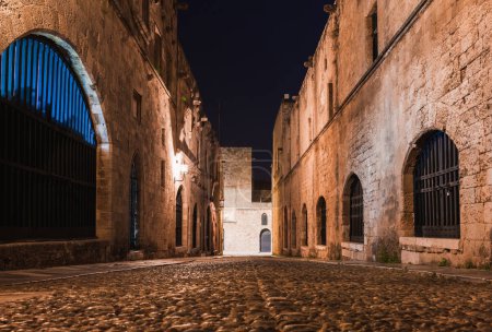 Photo for Night photo of ancient street of the Knights in Rhodes city on Rhodes island, Dodecanese, Greece. Stone walls and bright night lights. Famous tourist destination in South Europe - Royalty Free Image