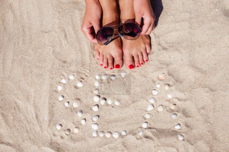 Téléchargez les photos : Portrait de plage de belle femme mince bronzée sexy relaxant dans la journée chaude ensoleillée d'été. Fermer les jambes avec du sable clair. Lifestyle concept de vacances tropicales de luxe. - en image libre de droit