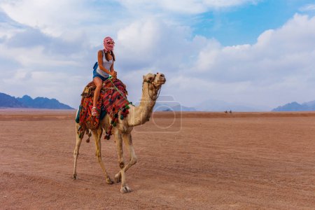 Foto de Mujer turista en ropa árabe tradicional con camello en el desierto del Sinaí, Sharm el Sheikh, Península del Sinaí, Egipto
. - Imagen libre de derechos