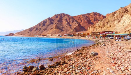 Téléchargez les photos : Plage ensoleillée sur la côte de la mer Rouge à Dahab, Sinaï, Egypte, Asie en été chaud. Destination touristique célèbre Blue Hole près de Sharm el Sheikh. Lumière brillante ensoleillée - en image libre de droit