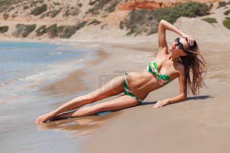 Téléchargez les photos : Gros plan belle femme sexy à la plage. Corps de fitness idéal, peau bronzée perect de fille glamour. Bikini coloré créatif et accessoires à la mode. Manucure vernis gel blanc - en image libre de droit