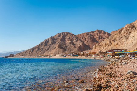 Téléchargez les photos : Plage ensoleillée sur la côte de la mer Rouge à Dahab, Sinaï, Egypte, Asie en été chaud. Destination touristique célèbre Blue Hole près de Sharm el Sheikh. Lumière brillante ensoleillée - en image libre de droit