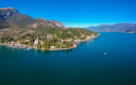 Téléchargez les photos : Vue aérienne paysage sur le magnifique lac de Côme à Tremezzina, Lombardie, Italie. Petite ville pittoresque avec des maisons traditionnelles et de l'eau bleue claire. Vacances touristiques d'été en station balnéaire riche avec beau port - en image libre de droit