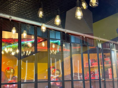 Foto de Un interior de restaurante lleno de multitud de luces colgando del techo, iluminando el espacio y creando un ambiente vibrante para los comensales. Las luces proyectan un cálido resplandor sobre las mesas y el suelo, añadiendo un toque de elegancia al comedor exp - Imagen libre de derechos