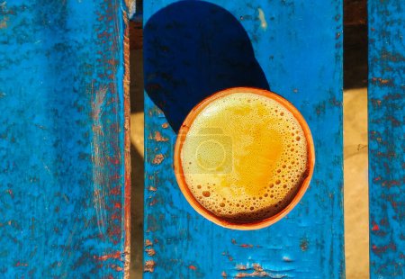 Téléchargez les photos : Vue de dessus d'un expresso mousseux dans une tasse en céramique sur un fond bleu coloré avec texture. - en image libre de droit