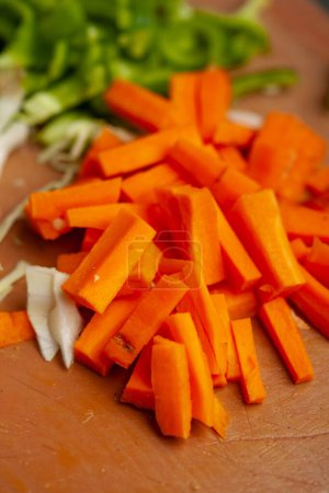 Freshly chopped carrots on a wooden cutting board, ingredients prep for cooking.