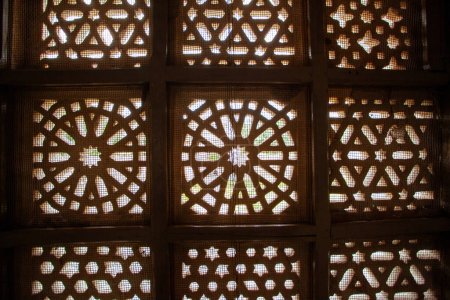 Photo for Beautifully crafted wooden lattice window allows sunlight to pattern the surface with cultural design at Mandu, India - Royalty Free Image
