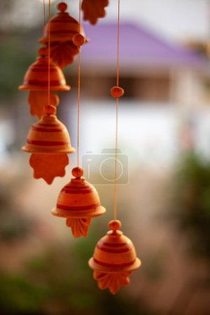 Une rangée de cloches suspendues à une corde. Les cloches sont orange et ont un dessin de feuille. Scène paisible et apaisante