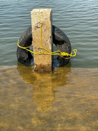 Neumático de goma negro atado con cuerda amarilla, presa de Gangapur, Nashik Maharashtra