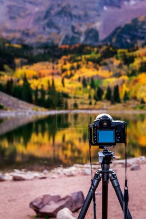 Photo for Professional camera and autumn aspen trees reflected in the lake. Maroon bells at autumn season in in Aspen Colorado, USA. Maroon bells, USA - September 23 2018. - Royalty Free Image