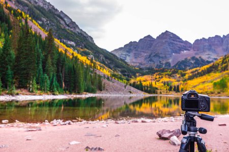 Photo for Professional camera and autumn aspen trees reflected in the lake. Maroon bells at autumn season in in Aspen Colorado, USA. Maroon bells, USA - September 23 2018. - Royalty Free Image