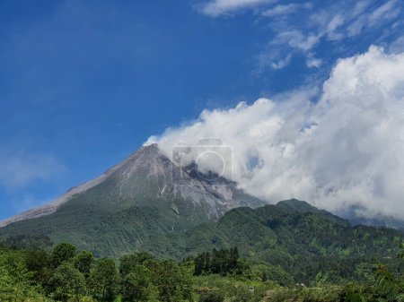 Photo du mont Merapi pendant la journée émettant de la fumée. Cette montagne est située sur le côté nord de la ville de Yogyakarta