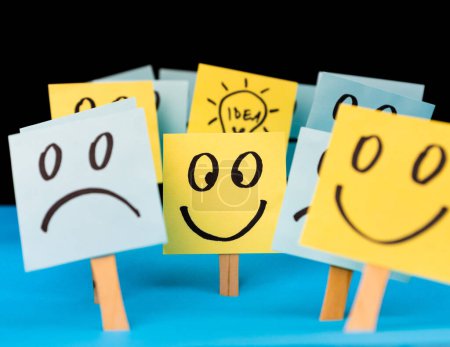 Klebezettel mit handgezeichneten Smiley-Gesichtern, traurigen Gesichtern und Glühbirnen. Positives Denken, Inspiration und Ideenkonzept. Positiver Geist überwindet Negatives