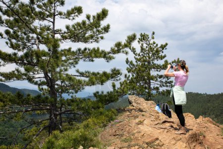 Touristenmädchen fotografiert mit Smartphone beim Wandern in der Natur auf dem Gipfel des Berges