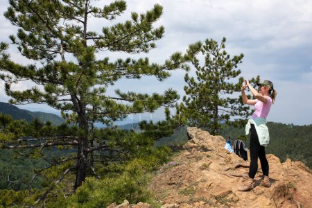 Touristenmädchen fotografiert mit Smartphone beim Wandern in der Natur auf dem Gipfel des Berges