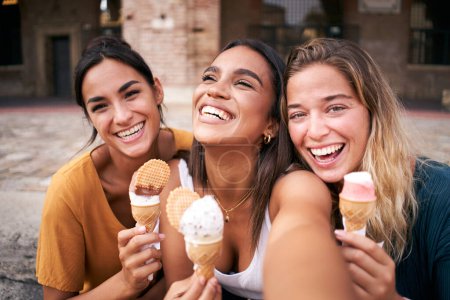 Foto de Tres jóvenes mujeres hipster sonrientes con ropa de verano. Chicas tomando fotos autorretrato selfie en el teléfono inteligente.Modelos posando en la calle.Mujer mostrando emociones positivas en la cara. Foto de alta calidad - Imagen libre de derechos