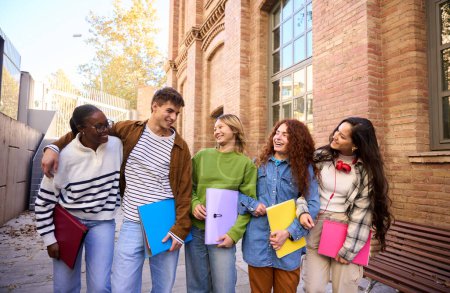 Téléchargez les photos : Groupe multiracial d'étudiants erasmus joyeux profitant de temps libre. De jeunes amis réunis à l'extérieur du campus universitaire et se regardant en souriant. Génération z collègues et relations avec les jeunes - en image libre de droit