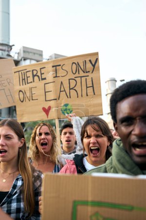 Grupo vertical multirracial de personas no conformes manifestación contra las fábricas de contaminación enojado gritando eslogan con varios mensajes de pancartas sobre el calentamiento global. Activistas de personas en comunidad