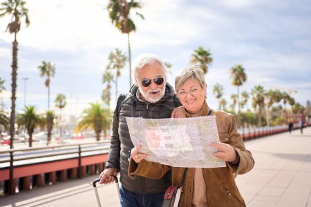 Ein älteres kaukasisches Touristenpaar lächelt mit einer Reisekarte in der Hand und sucht gemeinsam nach interessanten Orten. Senior Mann und Frau stehen in der Stadt Straße genießen Rentner Urlaub. Erwachsene Touristiker 