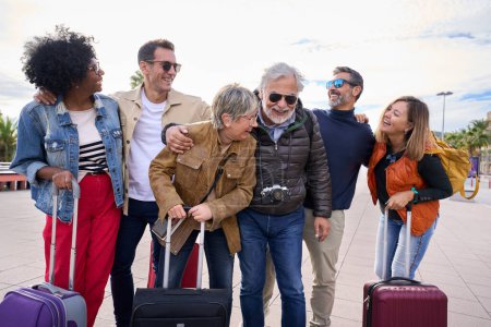 Eine Gruppe aufgeregter Touristenfreunde mittleren Alters amüsiert sich und lacht gemeinsam auf Reisen. Ältere Menschen genießen fröhlich sonnige Winterreisen. Mehrgenerationenfamilie