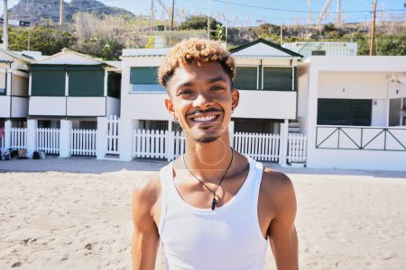Porträt eines glücklichen jungen Mannes aus Lateinamerika, der am Strand in die Kamera lächelt. Urlaubsleben der Generation Z, Urlaub und Sommer in einer Küstenstadt