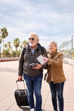 Vertikal ältere kaukasische Touristenpaar lächelnd schauen und zeigen Orte. Eine ältere Frau und ein Mann stehen in der Straße der europäischen Stadt und genießen den Rentnerurlaub. Senioren reisen glücklich